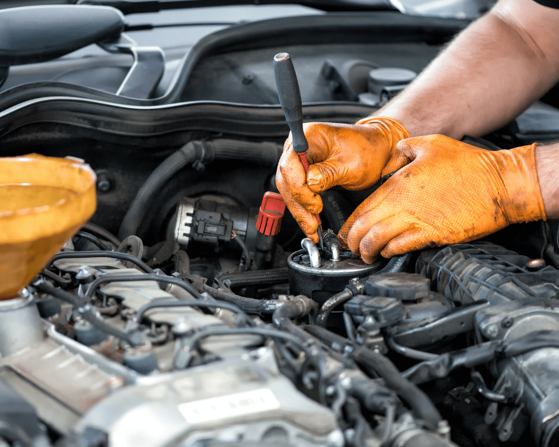 Mechanic wearing gloves working on a vehicle engine